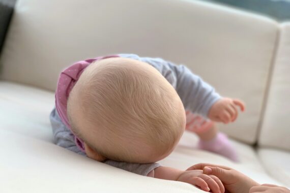 baby in blue long sleeve shirt lying on bed