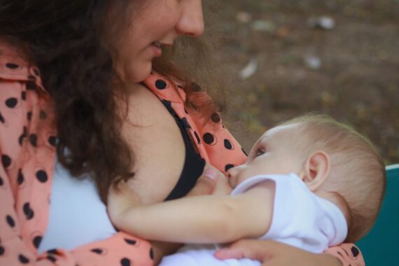woman in red and white polka dot shirt carrying baby